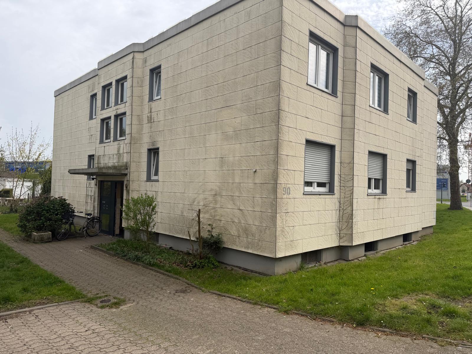 Eckansicht eines Mehrfamilienhauses mit unterschiedlich großen Fenstern